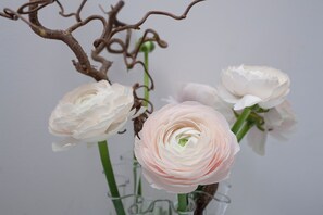 A vase with white and pink flowers, a clear glass vase, and a brown branch. - Santa Margherita Guesthouse (Venice)