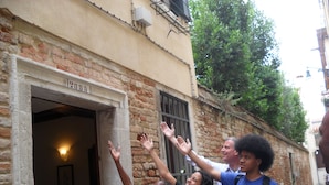 A narrow alley with a building entrance, a visible number "2885", and a person with raised hands. - Santa Margherita Guesthouse (Venice)