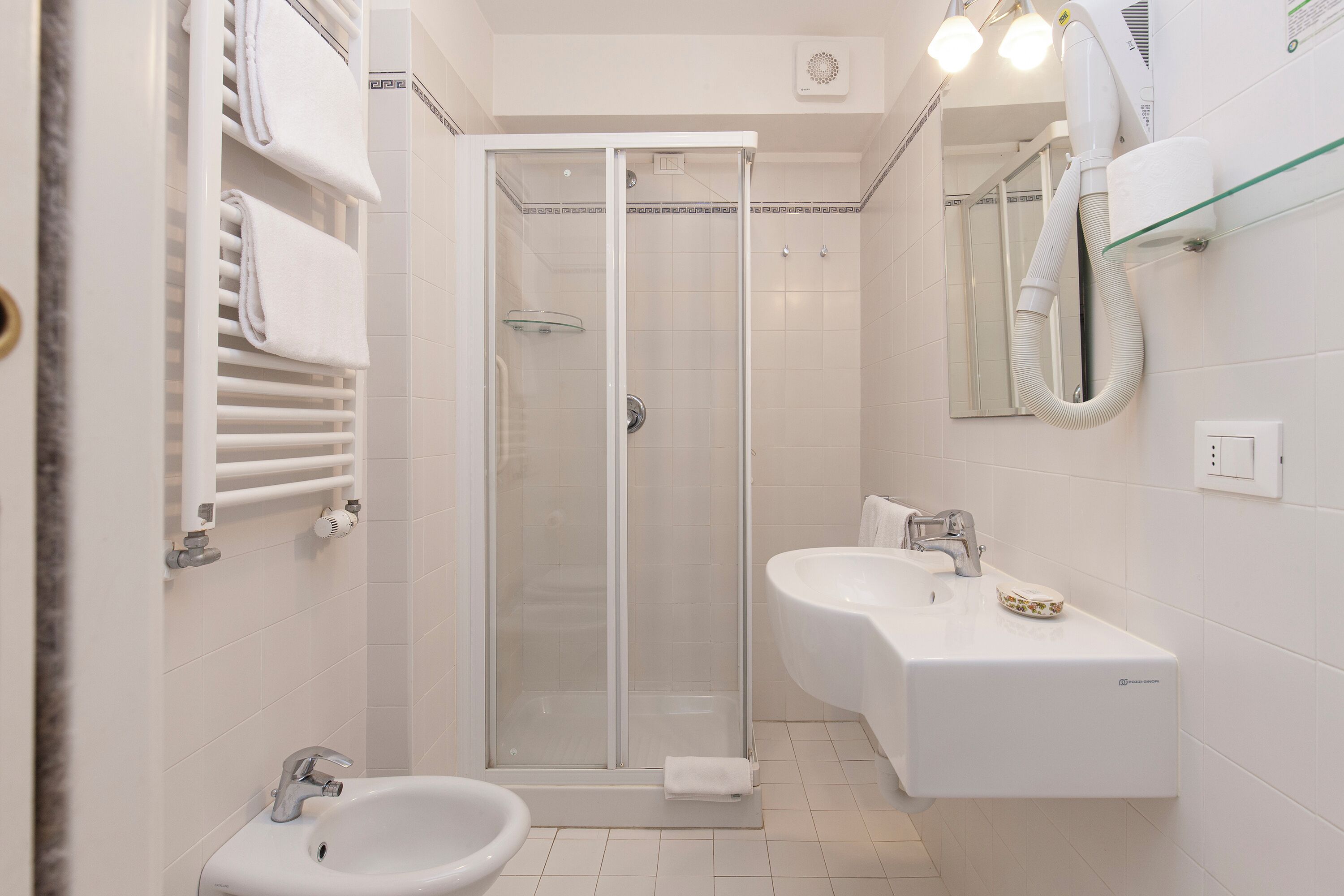 Une salle de bain moderne dotée d’une douche à parois de verre, d’un meuble-lavabo à deux vasques et d’un bidet.