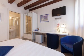 A hotel room with a bed, a desk with a chair, a TV, and a bathroom visible through an open door. - Santa Margherita Guesthouse (Venice)