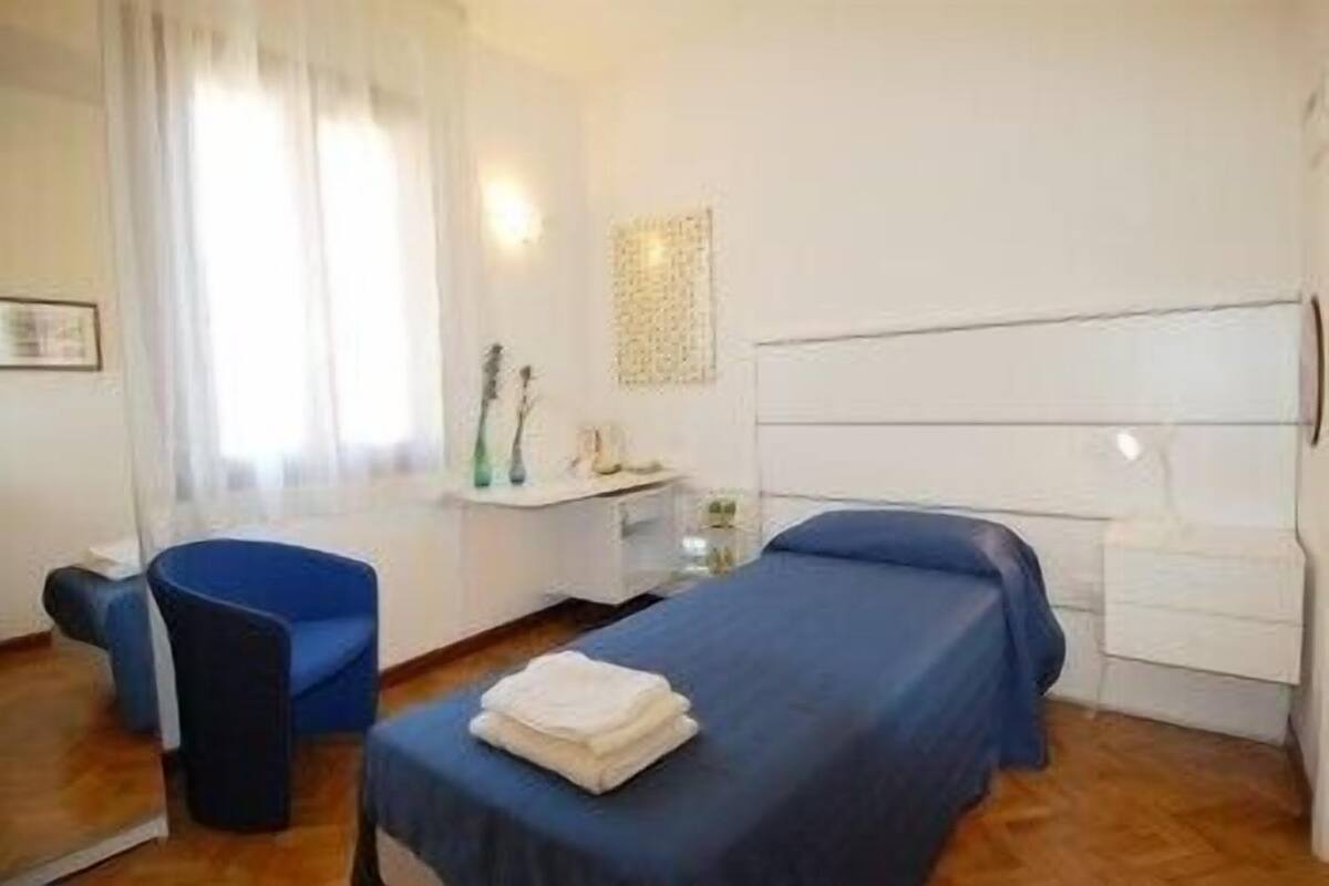 Een hotelkamer met een bed, stoel, bureau en spiegel.