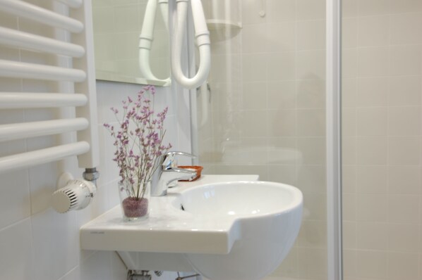 A bathroom with a white sink, a mirror, and a towel rack. - Santa Margherita Guesthouse (Venice)
