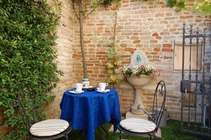 A small outdoor seating area with a blue tablecloth, two chairs, and a decorative planter with flowers. - Santa Margherita Guesthouse (Venice)
