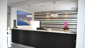 A modern reception area with a large painting, a black reception desk, and a potted plant. - Hotel Costamar (Torrox)