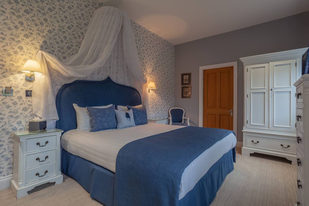 Un dormitorio con una cama grande, una mesita de noche, un armario y un dosel.