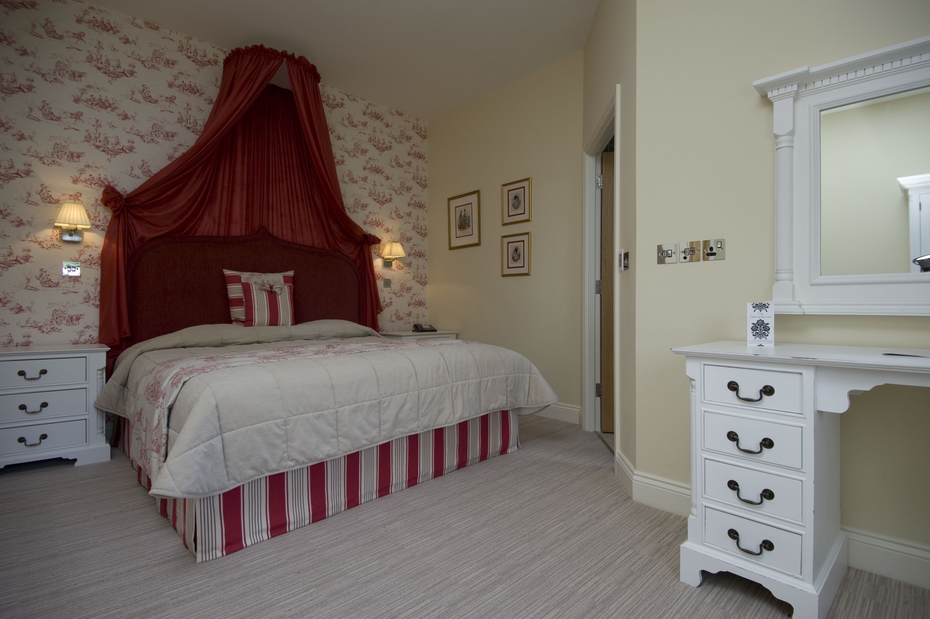 A bedroom with a canopy bed, a dresser with drawers, and a mirror.