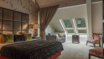 A bedroom with a large bed, a sofa, a chair, and a fireplace.