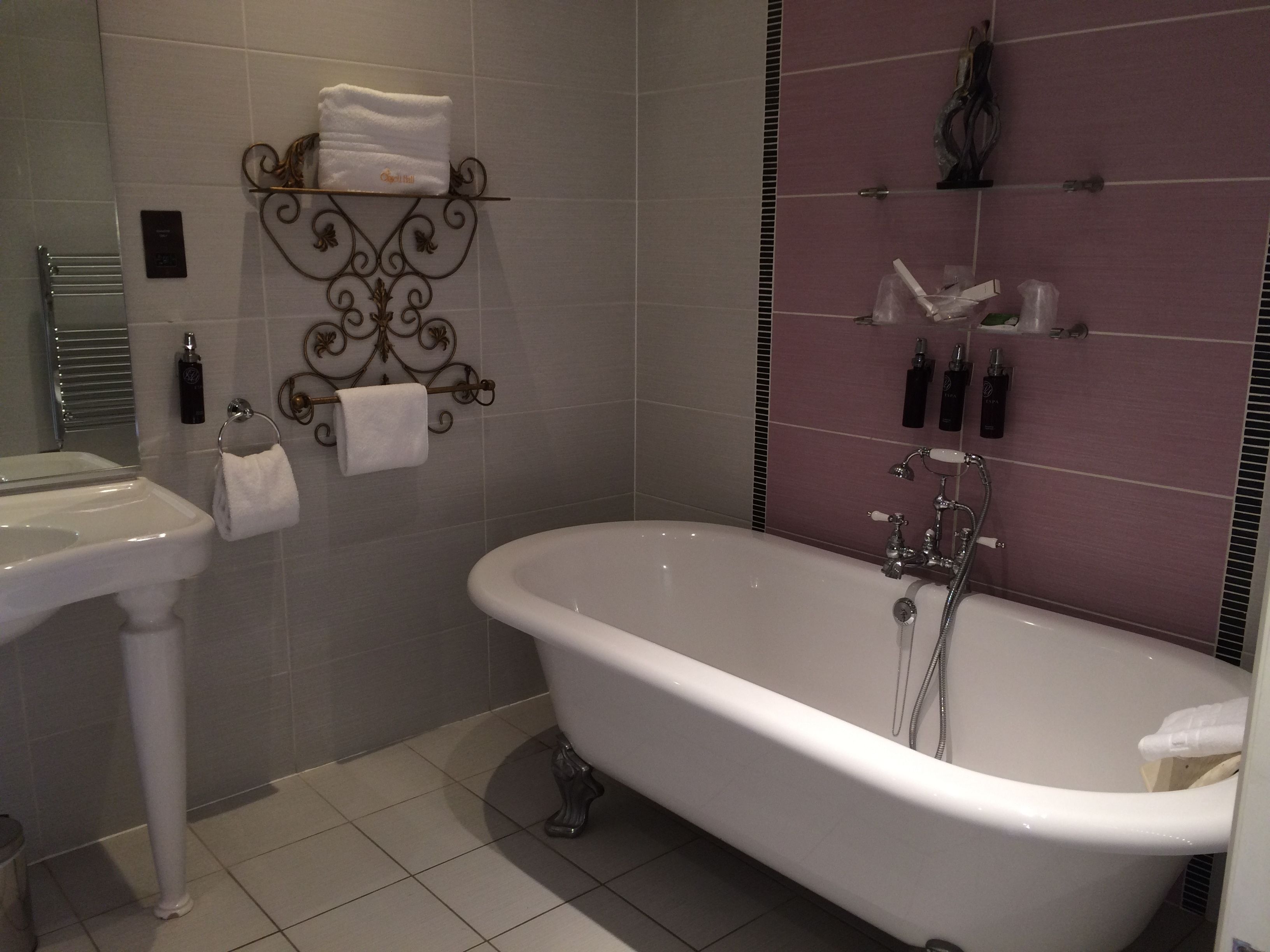 Un baño con una bañera independiente, un lavabo y un perchero para toallas.