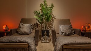 A room with two wicker sofas, a central plant, and a Buddha statue. - Orsett Hall Hotel (Grays)