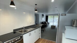 A modern kitchen with a built-in stove, sink, and refrigerator. - Fairway Motel and Apartments (Wanaka)