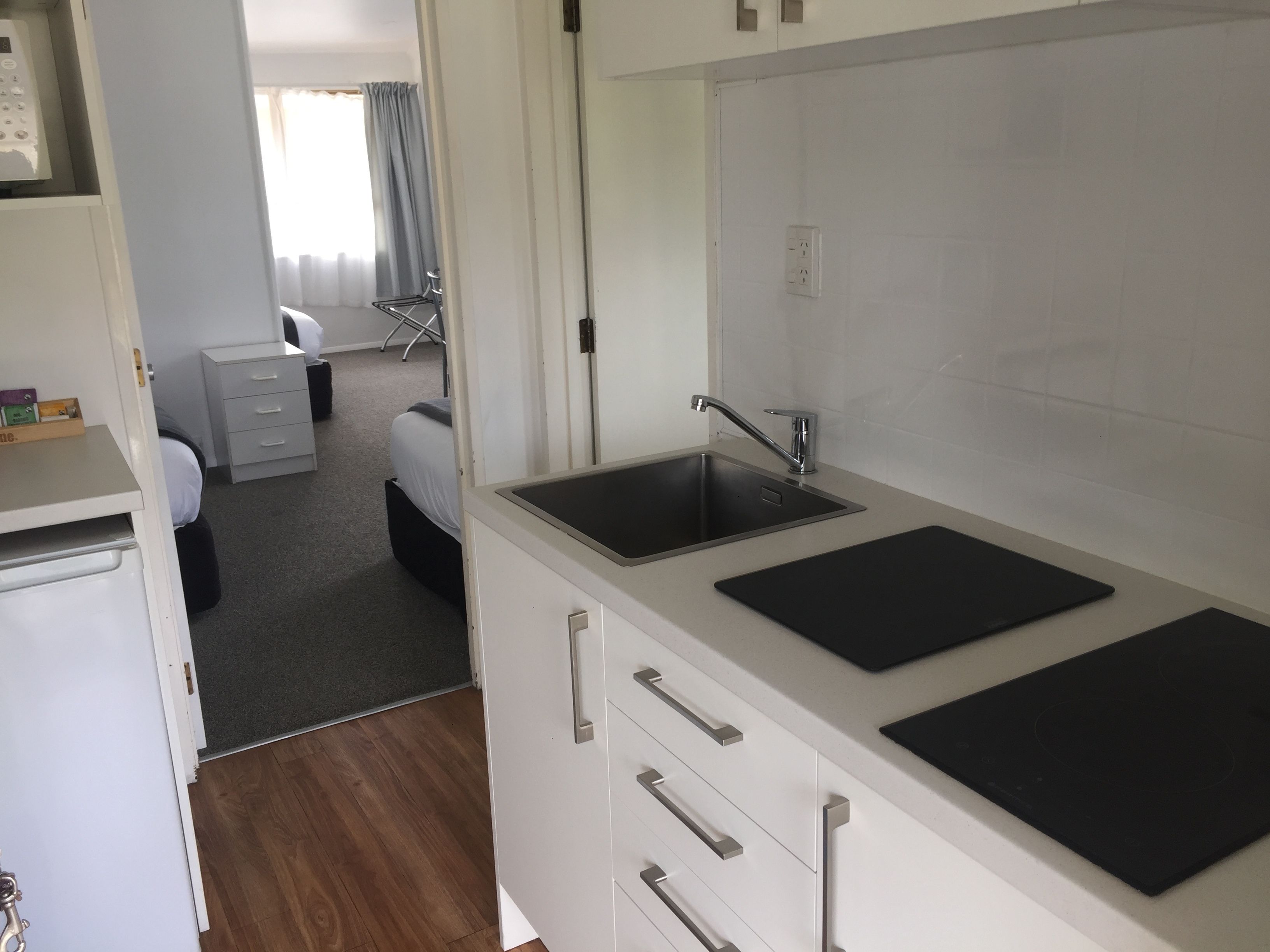 Una cocina moderna con un lavamanos doble, armarios blancos y una pequeña encimera.