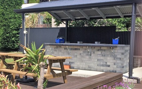 An outdoor patio area with wooden benches, a stone wall, and a covered seating area.