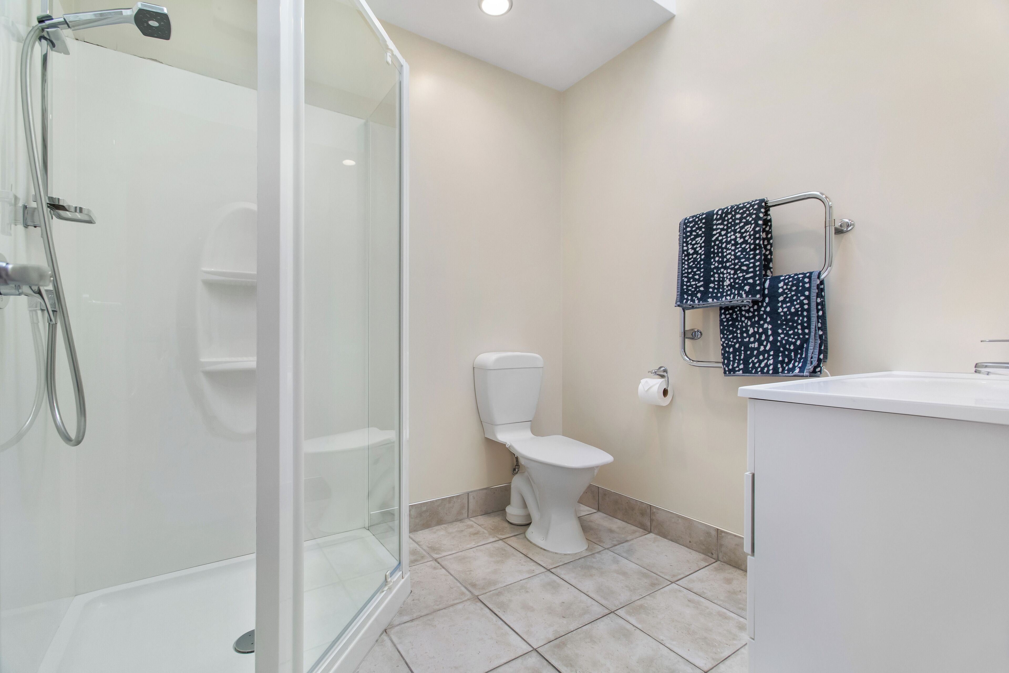 A modern bathroom with a glass-enclosed shower, a toilet, and a sink.