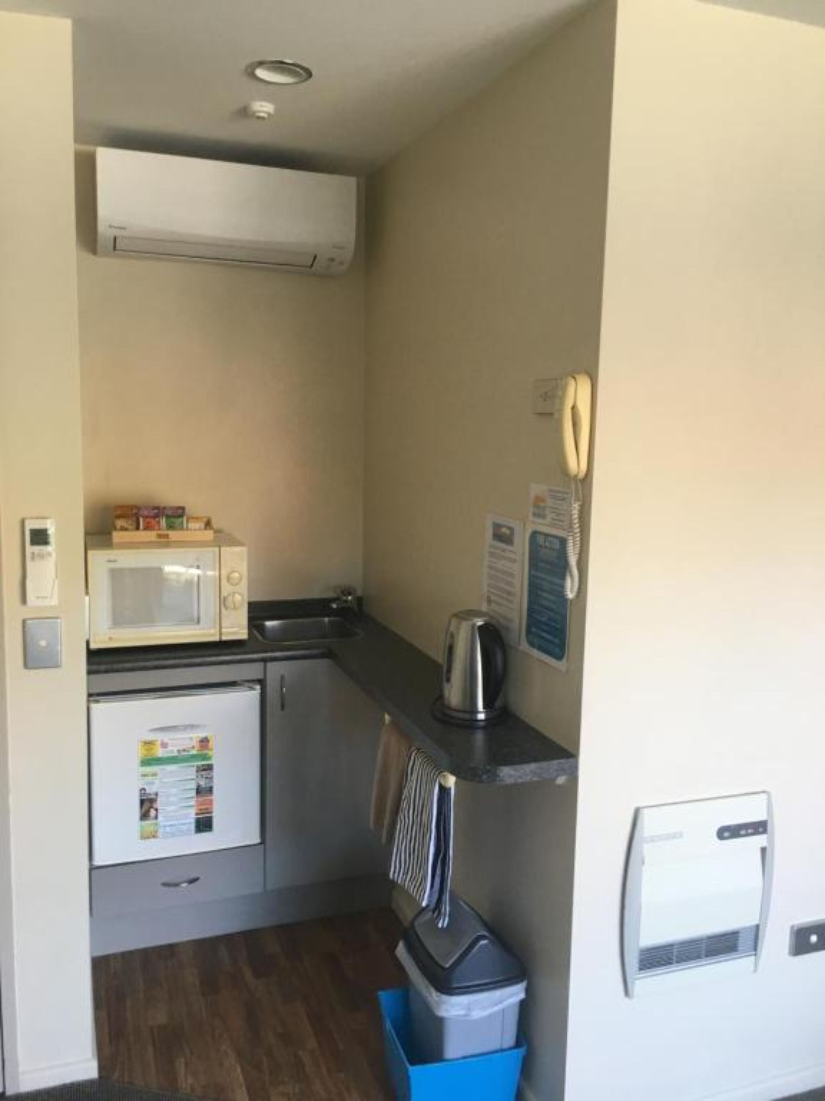 Eine kleine Küchenzeile mit Mikrowelle, Wasserkocher und kleinem Kühlschrank.