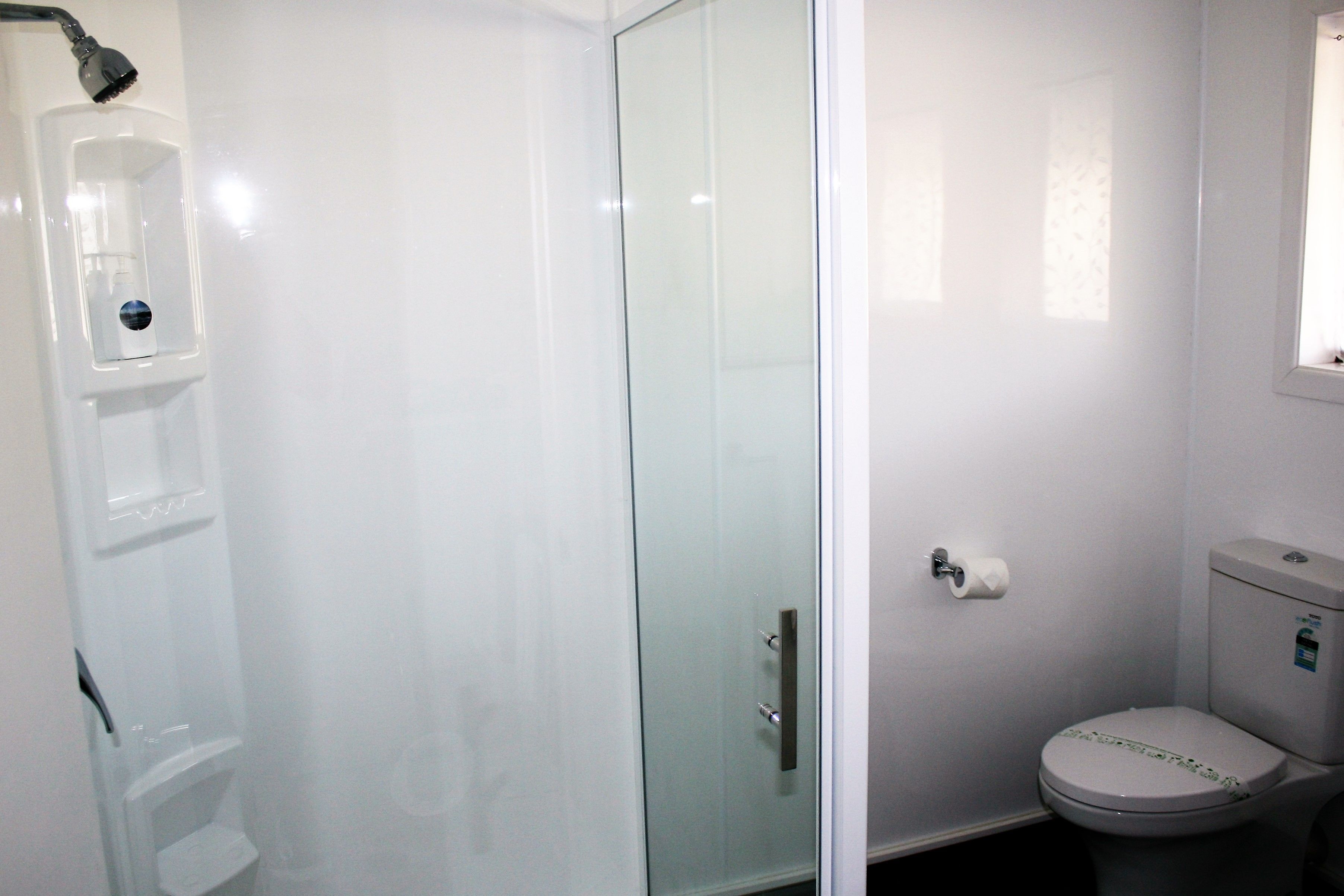 A bathroom with a glass-enclosed shower, a toilet, and a sink.