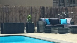 A pool area with a wicker sofa and a speaker. - Fairway Motel and Apartments (Wanaka)