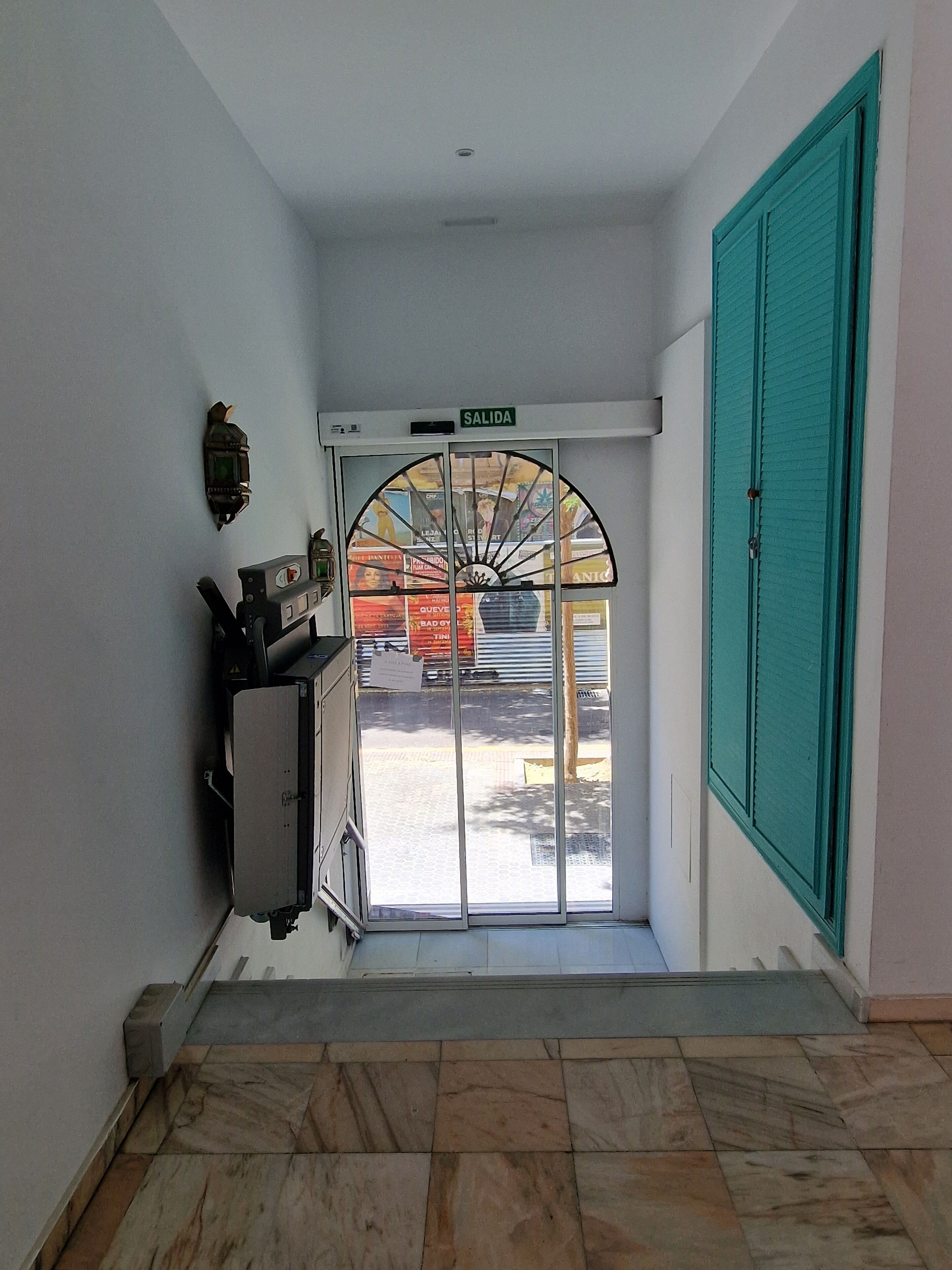 Un couloir avec une porte en verre portant l’inscription « SORTIE » et donnant sur l’extérieur.