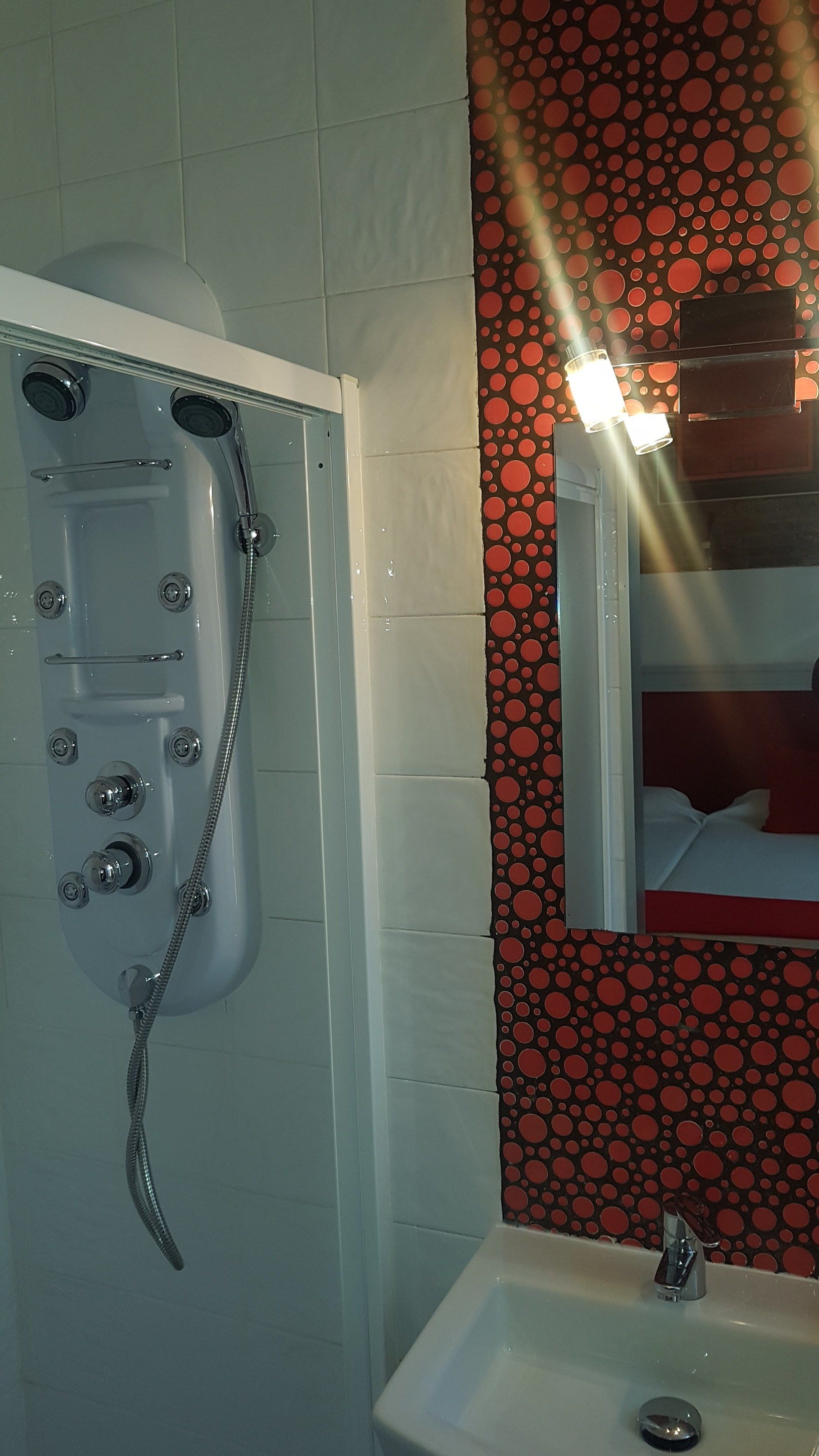 A bathroom with a shower, a sink, and a mirror.