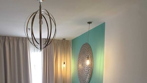 A hotel room with a bed, a sofa, a glass coffee table, and a decorative wall piece. - Hotel y Apartamentos Doña Lola (Seville)