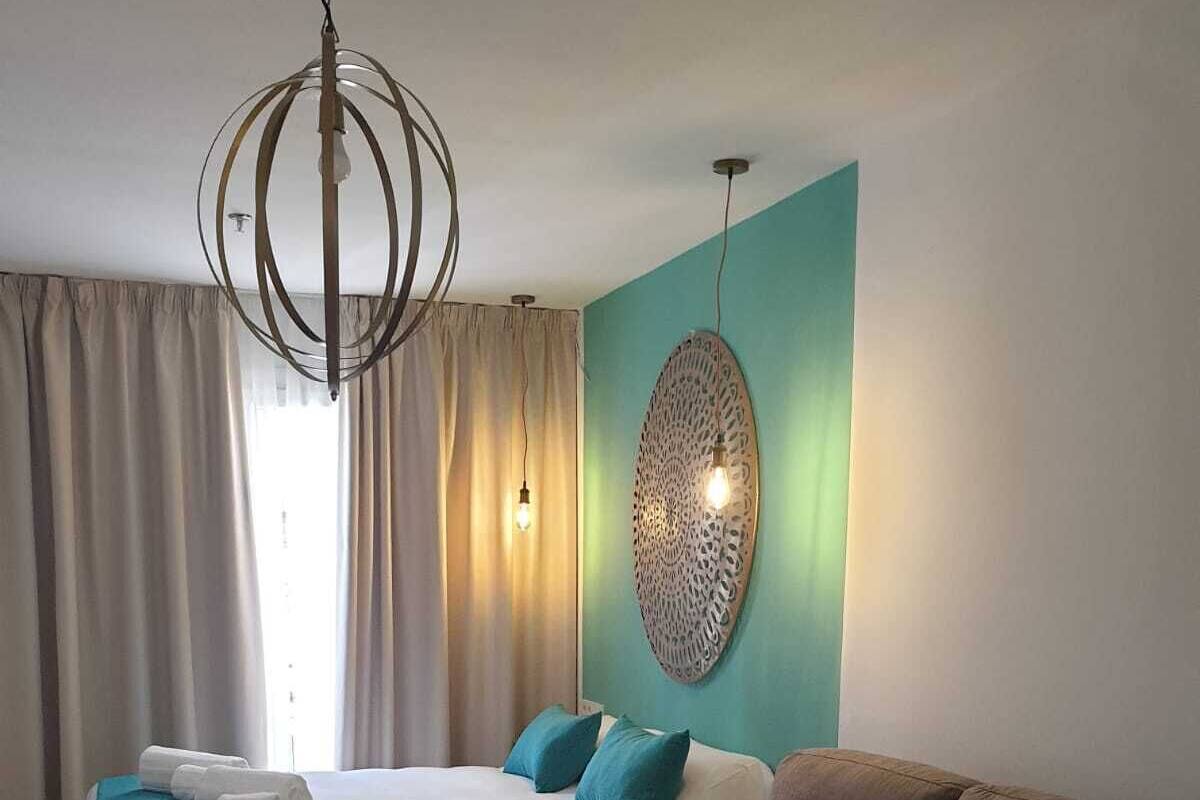 A hotel room with a bed, a sofa, a glass coffee table, and a decorative wall piece.