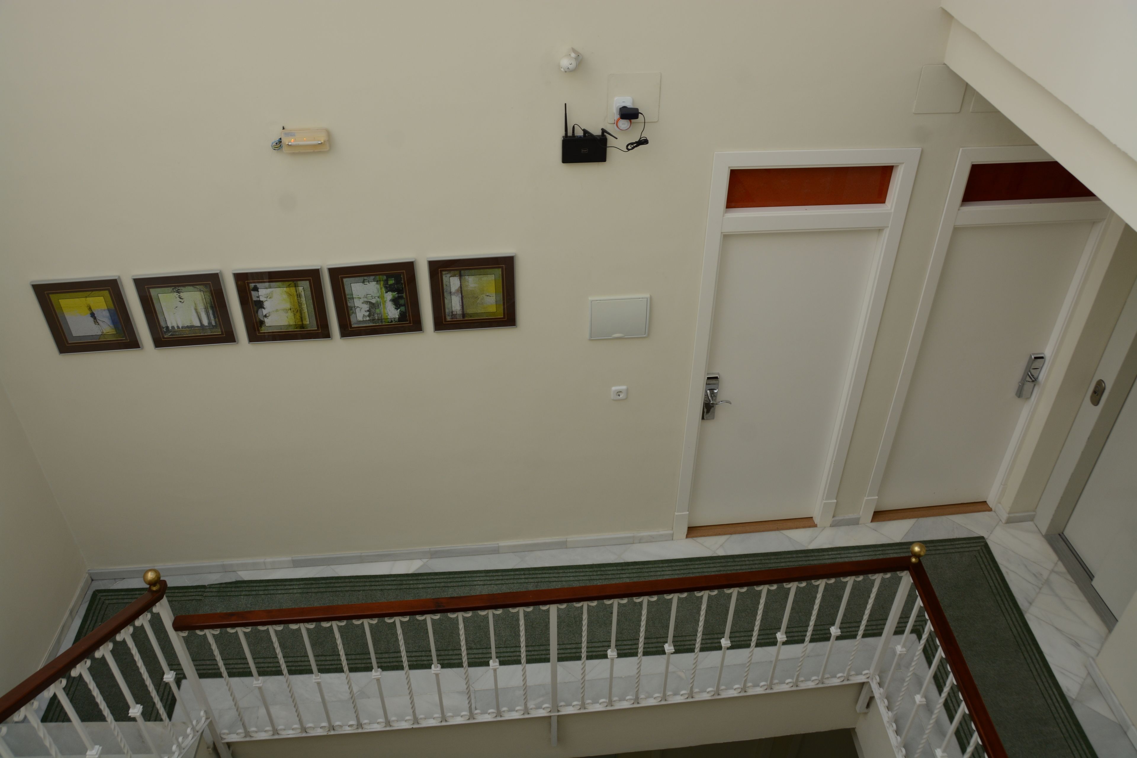 A staircase with a wooden handrail and white balusters, leading to a landing with framed pictures on the wall.