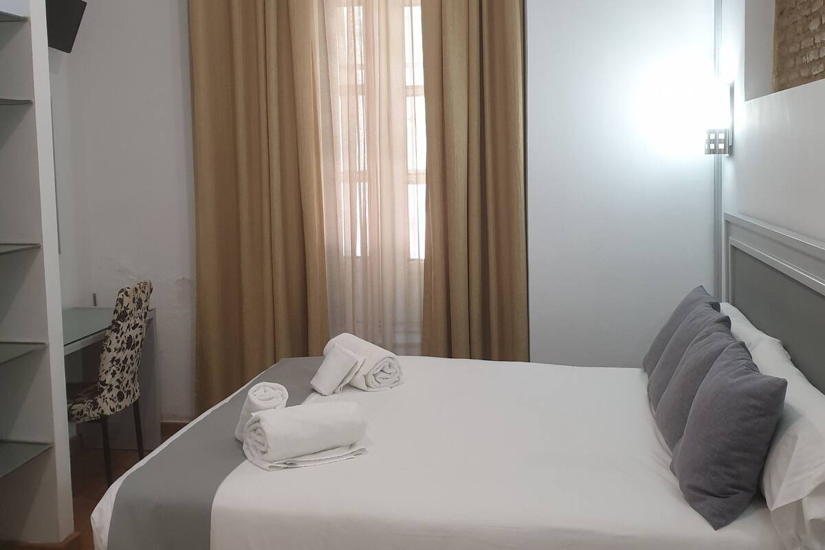 A hotel room with a bed, a desk, and a chair.