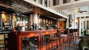 A bar area with a long counter, multiple stools, and a variety of bottles and glasses. - Royal Beacon Hotel (Exmouth)
