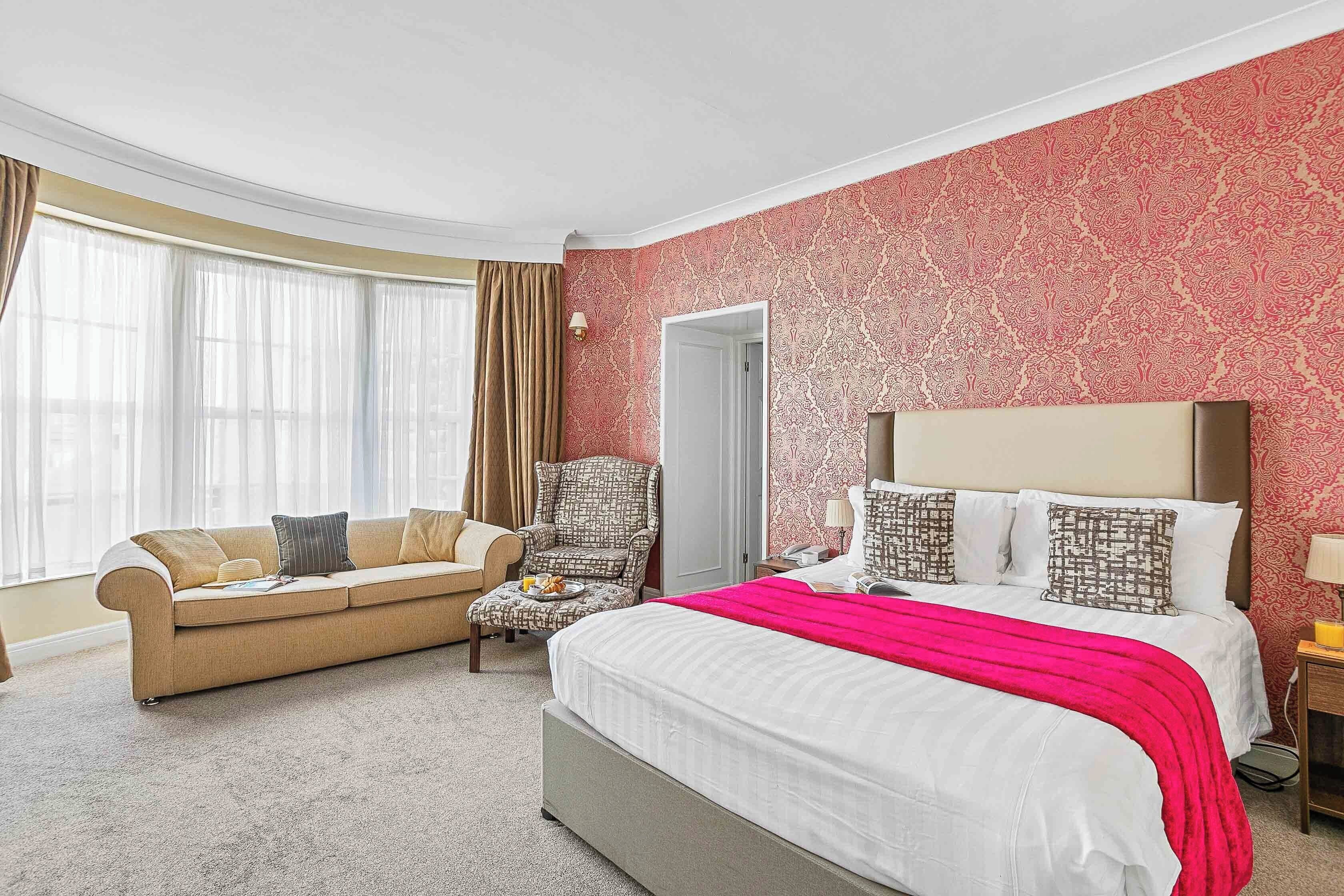 A hotel room with a bed, a sofa, a chair, and a desk.