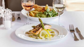 A plate of food with a fish and asparagus, accompanied by a glass of wine.