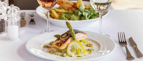 A plate of food with a fish and asparagus, accompanied by a glass of wine.