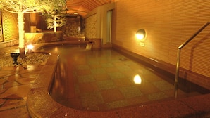 A spa area with a stone wall, a wooden bench, and a small pool. - APA Hotel & Resort Sapporo (Sapporo)