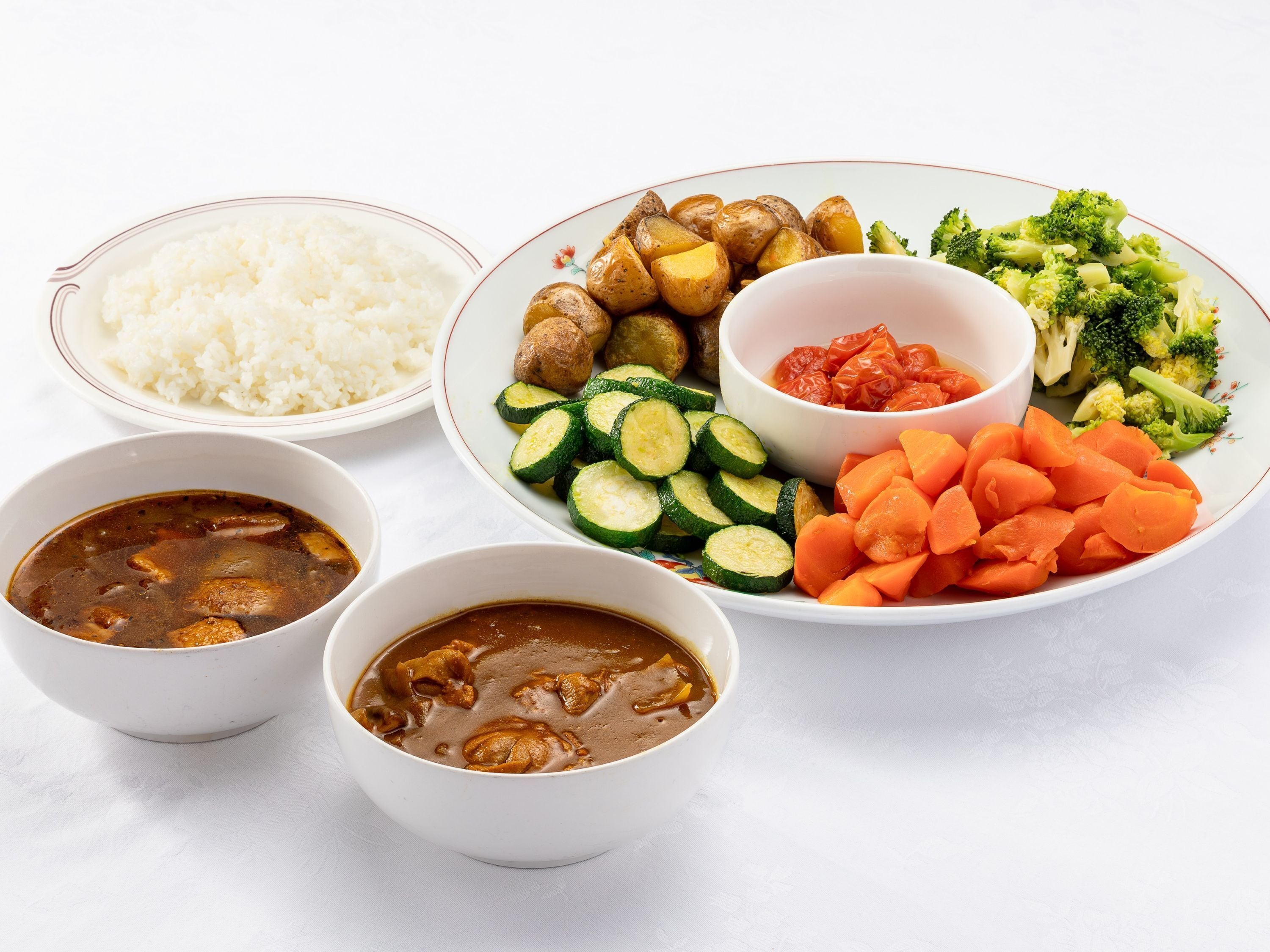 A meal with rice, soup, and a variety of vegetables.