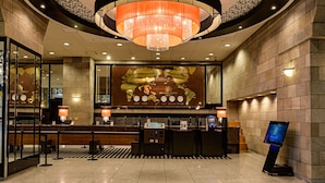 A hotel reception area with a large chandelier, a world map on the wall, and a digital information kiosk. - APA Hotel & Resort Sapporo (Sapporo)