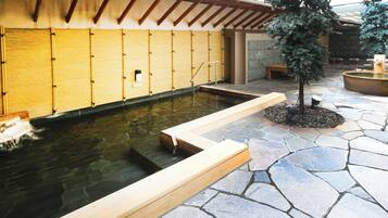 A traditional Japanese-style building with a stone-paved courtyard, a small pond, and a wooden deck.
