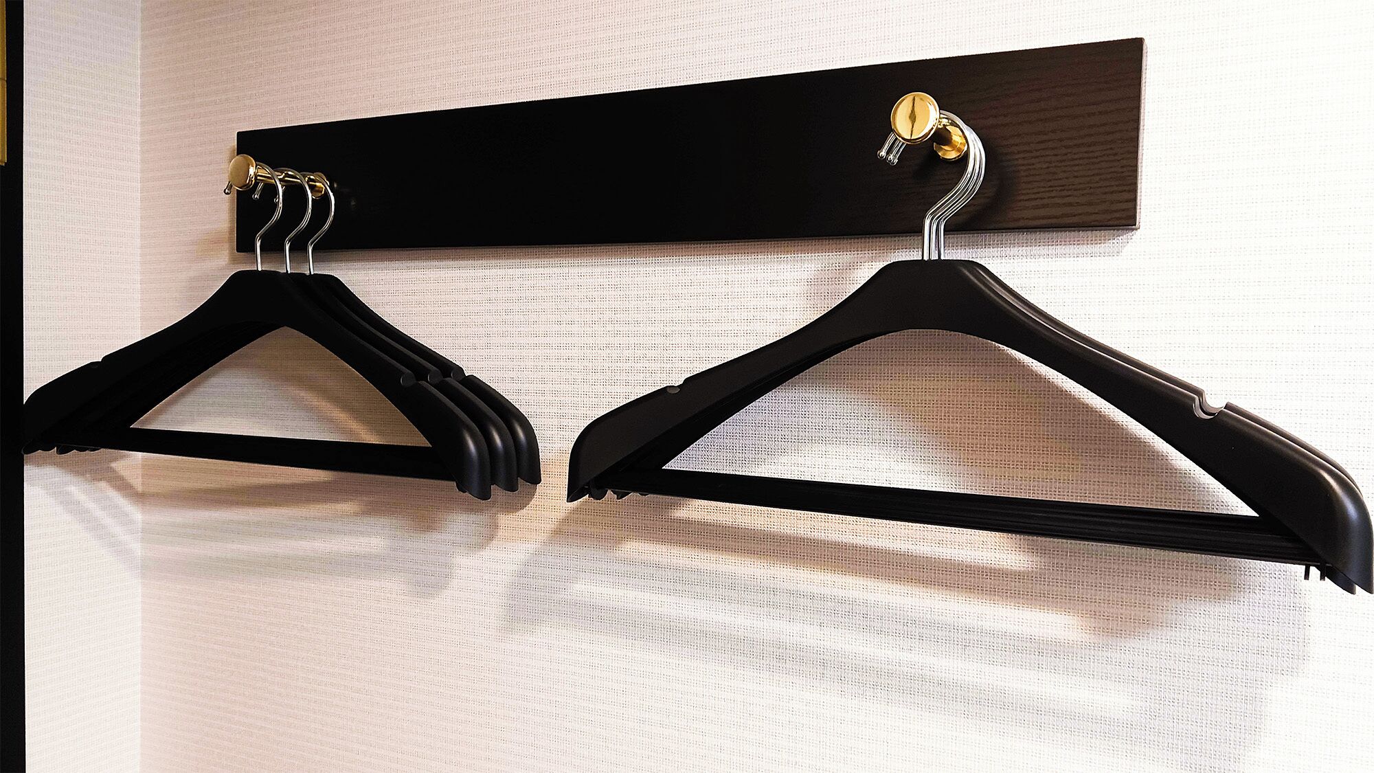 Two black hangers on a wall-mounted rack.