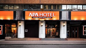 Entrada del APA HOTEL, con fachada de ladrillo y un letrero naranja llamativo.