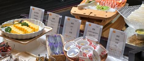 A variety of food items including pickled vegetables, tofu, and sashimi on a wooden table.