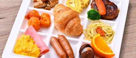 Um prato retangular branco com diversos itens de pequeno-almoço, incluindo ovos, salsicha, fiambre e legumes.