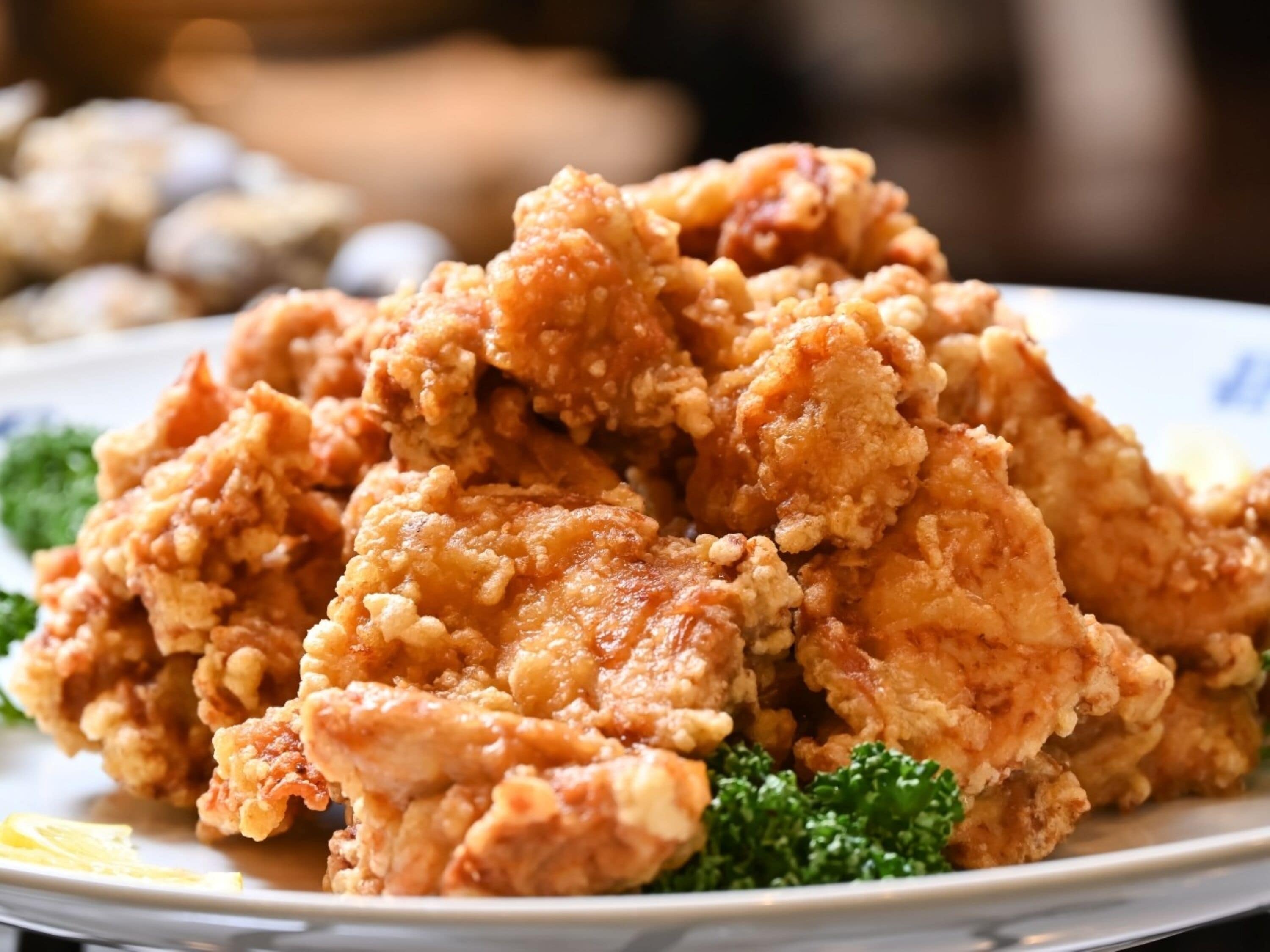 A plate of fried chicken with a garnish of green leaves.