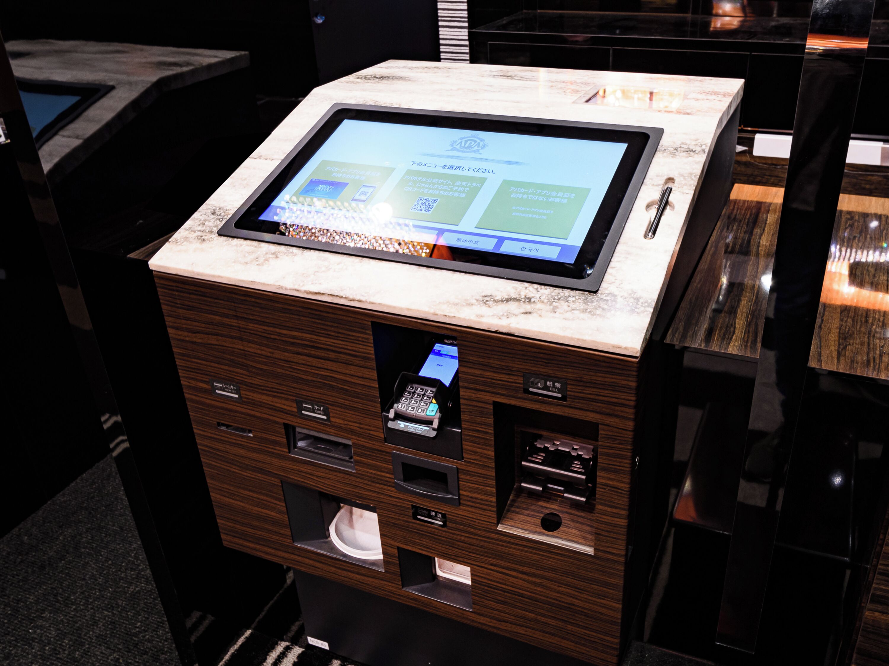 Quiosco de autoservicio con pantalla digital, lector de tarjetas y cajón para efectivo.