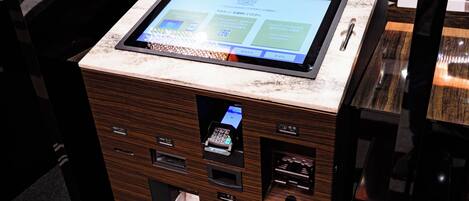 Quiosco de autoservicio con pantalla digital, lector de tarjetas y cajón para efectivo.