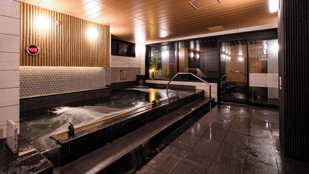 Un moderno espacio de spa con hidromasaje, paneles de madera y un termómetro digital.