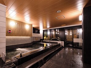 Un espace spa moderne doté d’un jacuzzi, de lambris en bois et d’un thermomètre numérique.