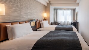 Una habitación de hotel con dos camas, un escritorio, una silla, una lámpara y un espejo.
