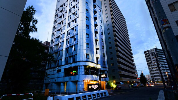 A multi-story hotel with a modern design, featuring balconies on each floor and a prominent sign at the top. - APA Hotel Sapporo Hosui Susukino Ekimae (Sapporo)