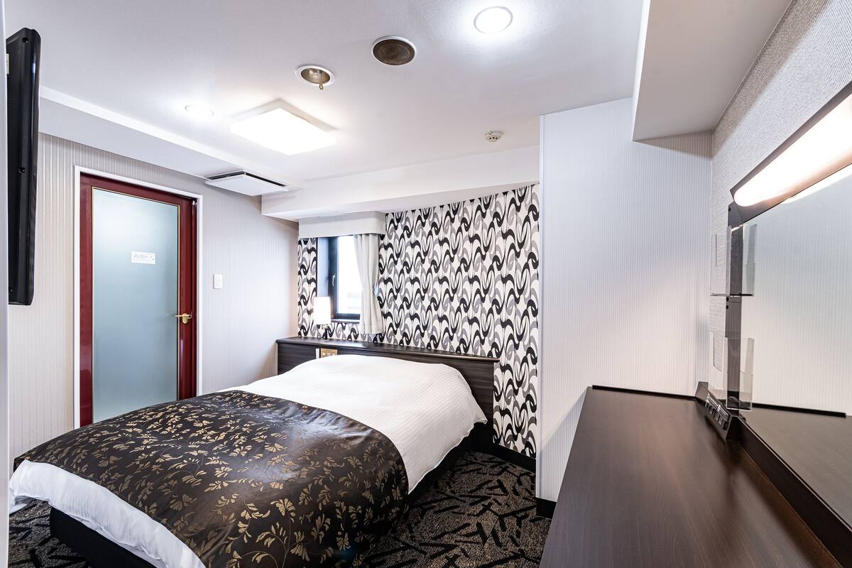 Ein Hotelzimmer mit Bett, Schreibtisch und Spiegel.