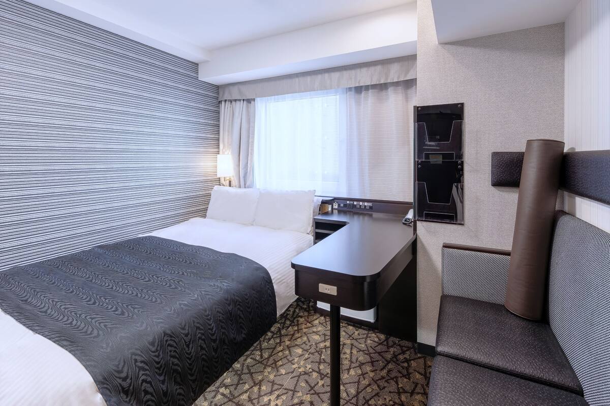 Ein modernes Hotelzimmer mit einem großen Bett, einem Schreibtisch und einer Sitzecke.