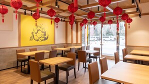 A restaurant interior with wooden tables and chairs, red lanterns hanging from the ceiling, and a yellow wall with a black illustration. - APA Hotel Sapporo Odori Ekimae Nishi (Sapporo)