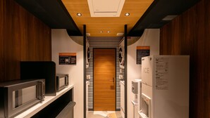 A modern kitchen with a microwave, refrigerator, and a wooden door leading to a pantry. - APA Hotel Sapporo Odori Ekimae Nishi (Sapporo)