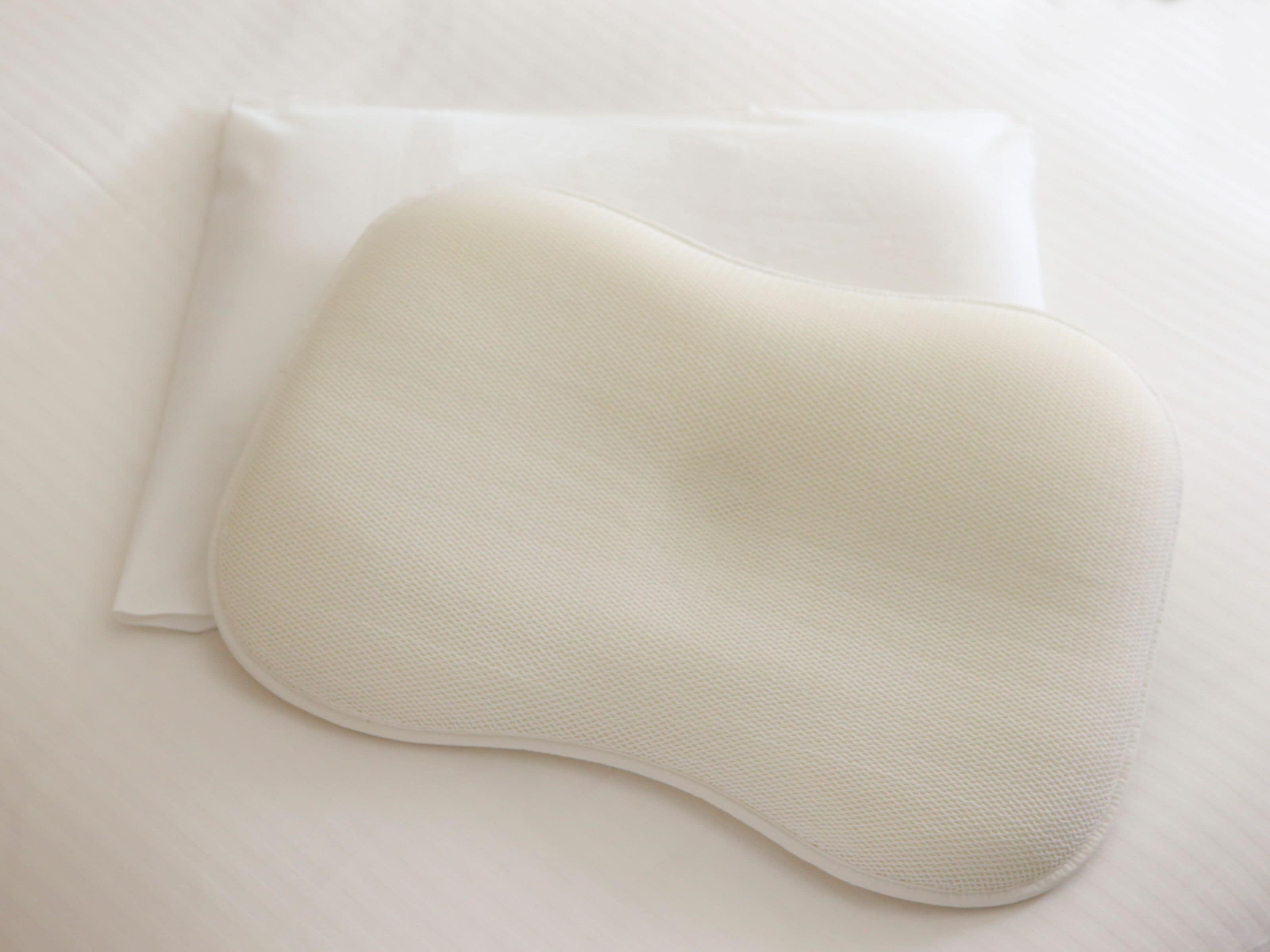 Een wit kussen en een witte kussensloop op een wit bed.
